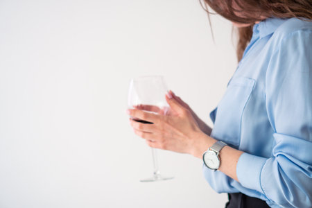 office girl in blue shirt and pearl necklace with glass of wineの写真素材