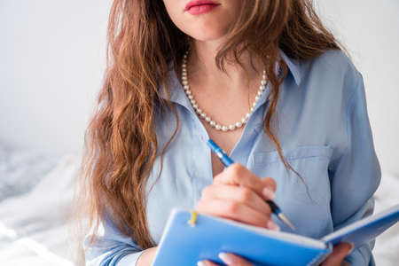 office girl in blue shirt and pearl necklace with blue notebookの写真素材