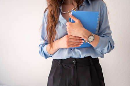 office girl in blue shirt and pearl necklace with blue notebookの写真素材