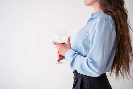 office girl in blue shirt and pearl necklace with glass of wineの写真素材
