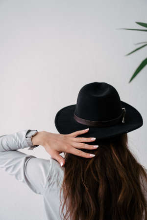 girl in a black hat on a white wall backgroundの写真素材