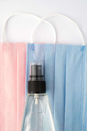 protective face masks and bottle of hand sanitizer on white background