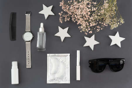 trendy flat lay: eye patches, cream, lipstick, wristwatch, sunglasses and a bouquet of dried flowers
