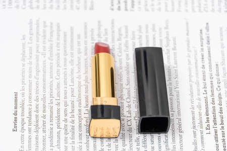 red lipstick of minimalist design in black and yellow packaging lies against the background of a fashion magazineの写真素材