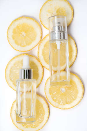 face care serum and cream on fresh yellow lemon slices on white background