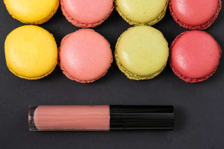 Macarons on dark background, colorful french cookies macarons and make up cosmetics