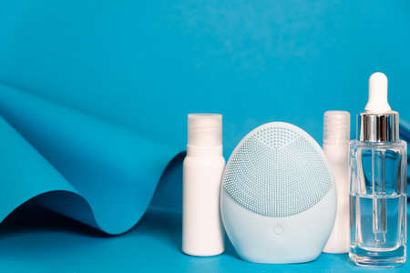 Art colorful geometry blue style and skin care cosmetics. Origami in a blue color and cosmetics in white and blue colors: serum, face cream, face tonic. Paper mock up and luxury cosmetic.の写真素材