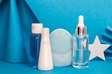 Art colorful geometry blue style and skin care cosmetics. Origami in a blue color and cosmetics in white and blue colors: serum, face cream, face tonic. Paper mock up and luxury cosmetic.の写真素材