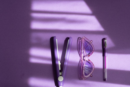purple flat lay: hair care tool, pen, sunglasses on a purple background and shadowsの写真素材