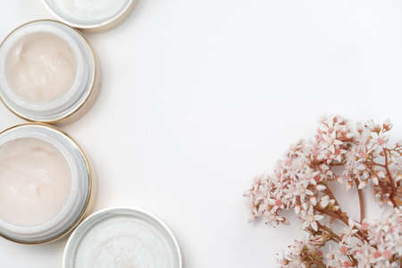 cosmetics for the face. eye cream and a bunch of pink flowers on a white background