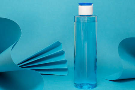 Art colorful geometry blue style and skin care cosmetics. Origami in a blue color and cosmetics in white and blue colors: serum, face cream, face tonic. Paper mock up and luxury cosmetic.の写真素材