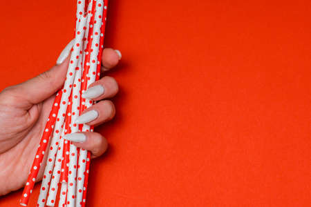 girl holding paper straw for drinks red and white on a red backgroundの写真素材