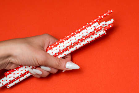 girl holding paper straw for drinks red and white on a red backgroundの写真素材