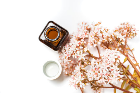 cosmetics for the face. eye cream and a bunch of pink flowers on a white backgroundの写真素材