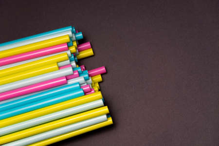 colorful cocktails straw for drinks in pink, yellow, blue colors on a dark background