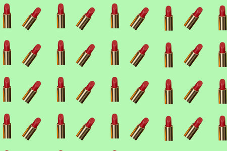 Creative pattern fashion photo of cosmetics beauty products red lipstick on a green backgroundの写真素材