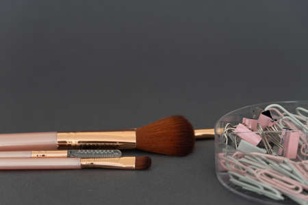 pink makeup brushes on a dark gray background. luxury cosmetics. pink and gray makeup tools and...