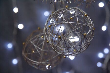 Silver Christmas globes hanging over a background of blurred lights.の写真素材