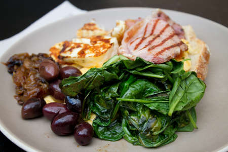 Breakfast with toast, scrambled eggs, spinach, Haloumi cheese, fried ham, Kalamata olives and...