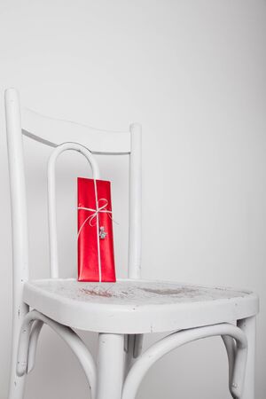 Red gift on old white chair with red silver ribbon and angelの写真素材