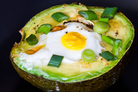 Eggs baked in avocado garnished with green onionsの写真素材