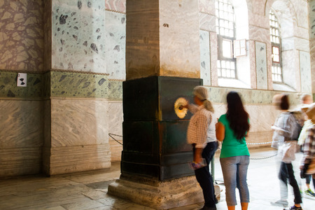 ISTANBUL, TURKEY - SEPTEMBER 23: People at the perspiring column (wishing, sweating, crying column) inside Hagia Sophia on September 23, 2014 in Istanbul, Turkeyのeditorial素材