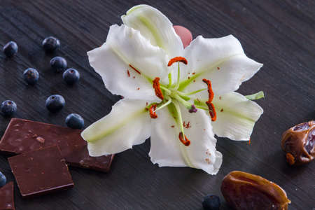 White lily with pink ribbon and dry dates, chocolate and blueberriesの写真素材