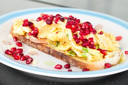 Close up of breakfast dish - omelette with green onion and ham, garnished with pomegranateの写真素材