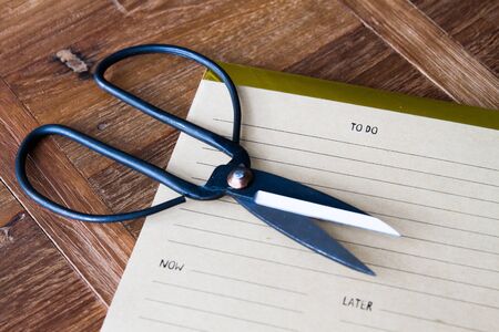 Vintage black scrissor with to do list over wooden background