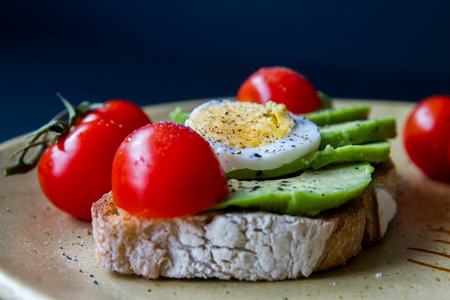 Slice of toast bread with avocado, eggs and cherry tomatoes