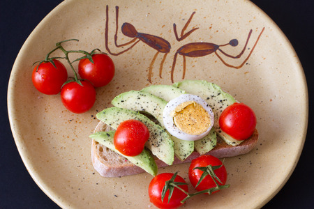 Slice of toast bread with avocado, eggs and cherry tomatoesの写真素材