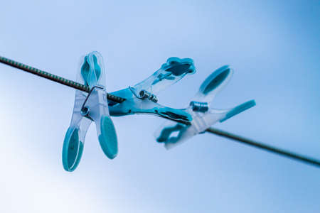 Close-up of differently colored pegs on washline over the blue skyのeditorial素材