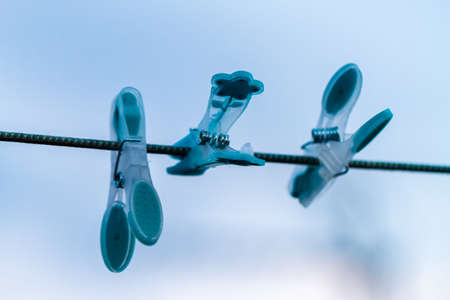 Close-up of differently colored pegs on washline over the blue skyのeditorial素材