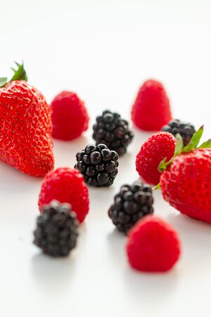Berries - strawberries, raspberries, blueberries, blackberries - on white background in natural lightの写真素材