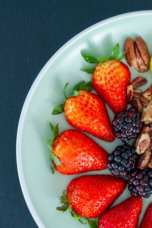 Breakfast plate with kiwi, raspberries, strawberries, blackberries and pecan nuts