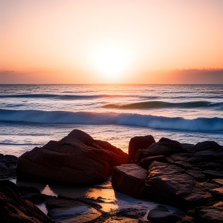 Sunset over the sea with rocks and waves on the foreground.の素材