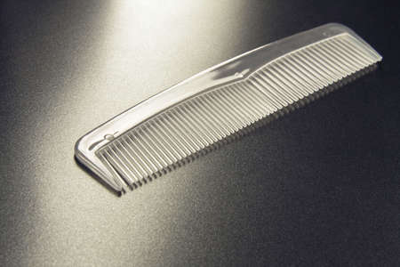 The transparent hairbrush lays on a grey background
