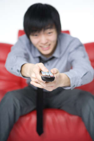 The smiling young man in a grey shirt watches TV