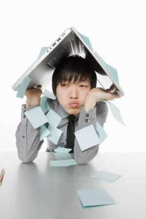 The young man sits at a table having hidden from problemsの写真素材