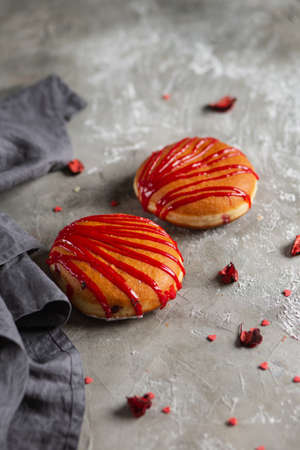 Two donuts sprinkled with powdered sugar on a wooden board