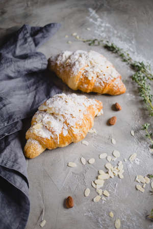 two fresh croissants on wooden board and gray napkin