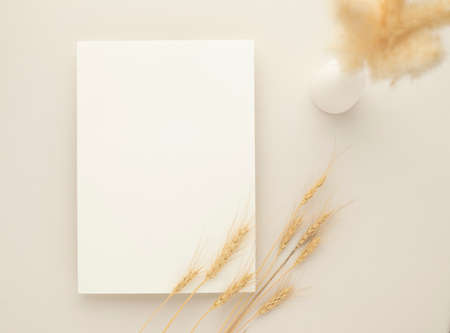 White invitation card mockup with a dried grass and ceramic vase on beige background, Minimal beige workplace composition, flat lay, mockupの写真素材