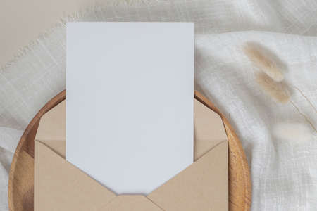 Blank paper cards, Blank greeting card invitation Mockup with craft envelope, Dried Bunny Tail grass on desk background, Minimal table workplace composition, flat lay, mockupの写真素材