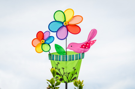 Colorful double pinwheel with a bird on the white sky