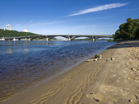 A piece of sandy beach  View of the bridge  In the background, high-rise buildings surrounded by greenery are reflected in the waters of the river の写真素材
