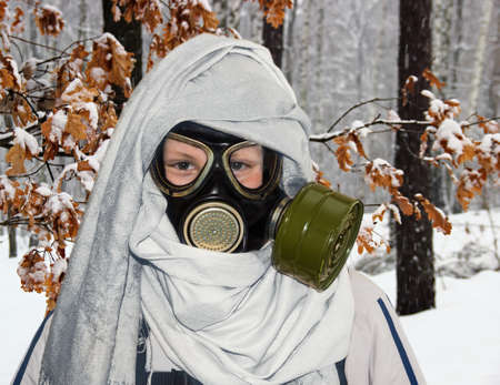 A boy plays in a stalker winter outdoors  He dressed gas mask and disguised as a sniper の写真素材