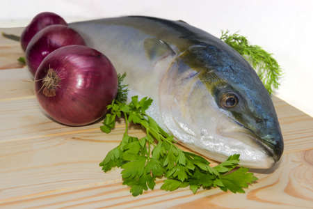 fresh fish with three heads of red onion and parsley on a wooden surface.の写真素材