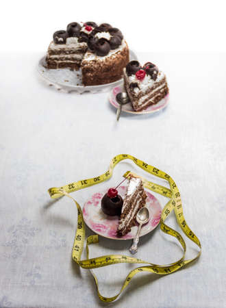 Tape measure and cakes in a saucers on the tableの写真素材