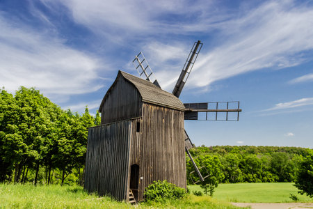 Old windmill on a background of forest and sky with blurred clouds. Ukrainian Museum of Folk Architecture and Life, Kiev, Ukraine.のeditorial素材