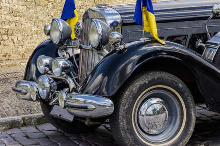 Fragment of the front of a retro car on a background of ancient stone fortress wallの写真素材
